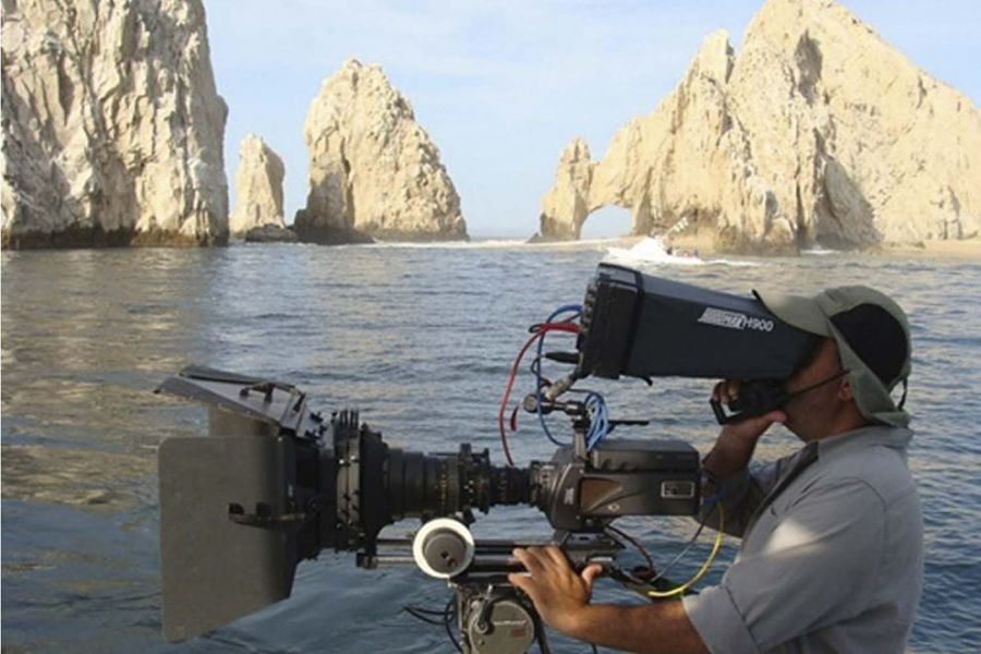A cameraman filming the iconic Los Arcos landmark in Cabo San Lucas.