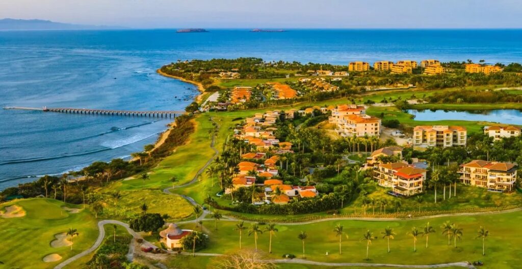 Aerial view of the El Encanto community within the Punta Mita gates, showing condo developments, villas, golf course, and Pacific Ocean shore.
