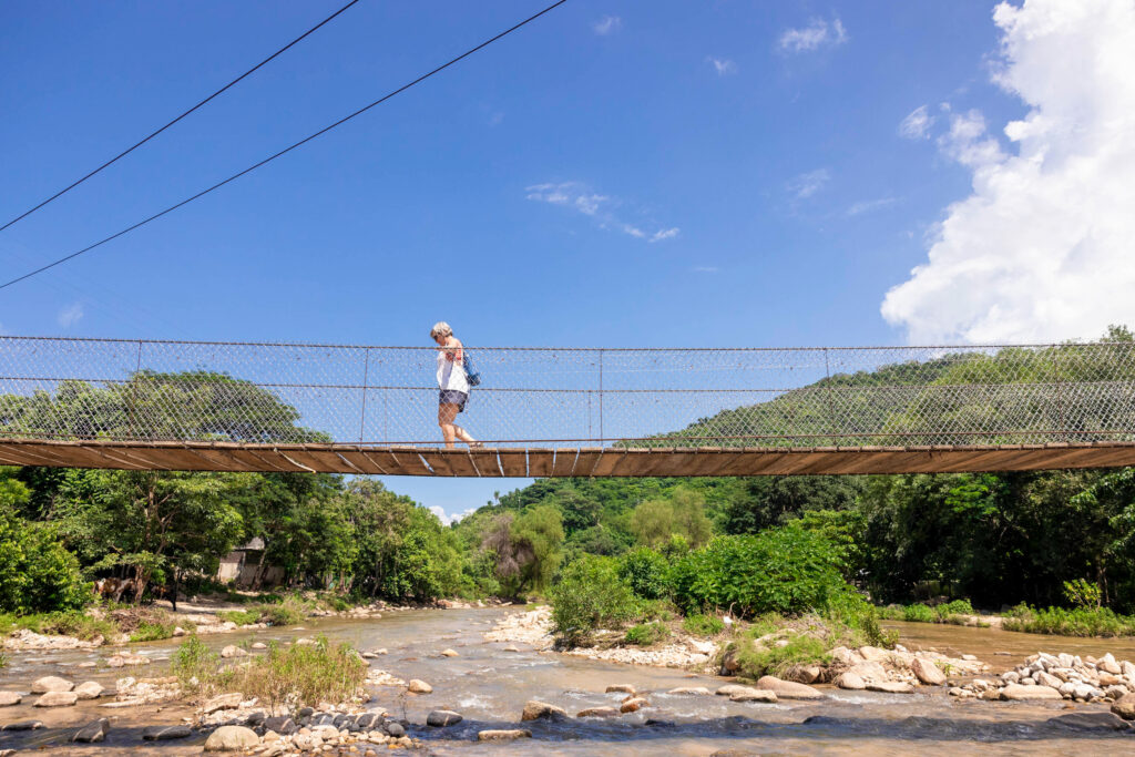 Tourist crossing the hanging bridge over Quimixto River.