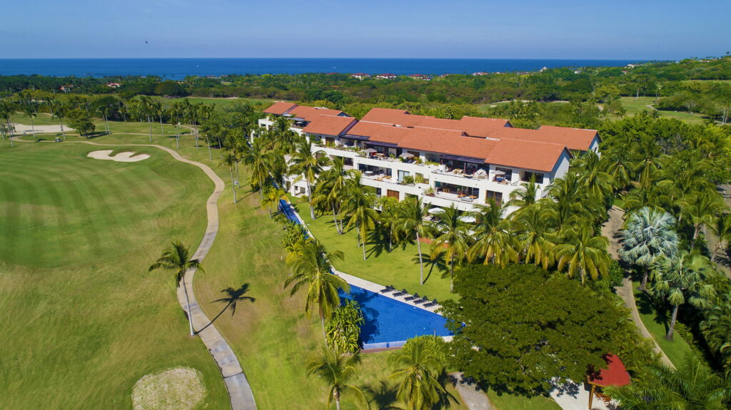 Scenic view of Las Terrazas condo building with pool, lush tropical gardens, and golf course in Punta Mita