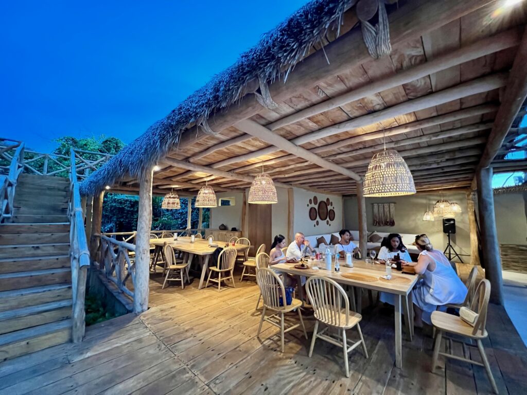 Guests sitting in Villa Mixto's outdoor dining palapa, enjoying an open house event under a captivating sunset, showcasing the villa's potential as an ideal Puerto Vallarta event venue.