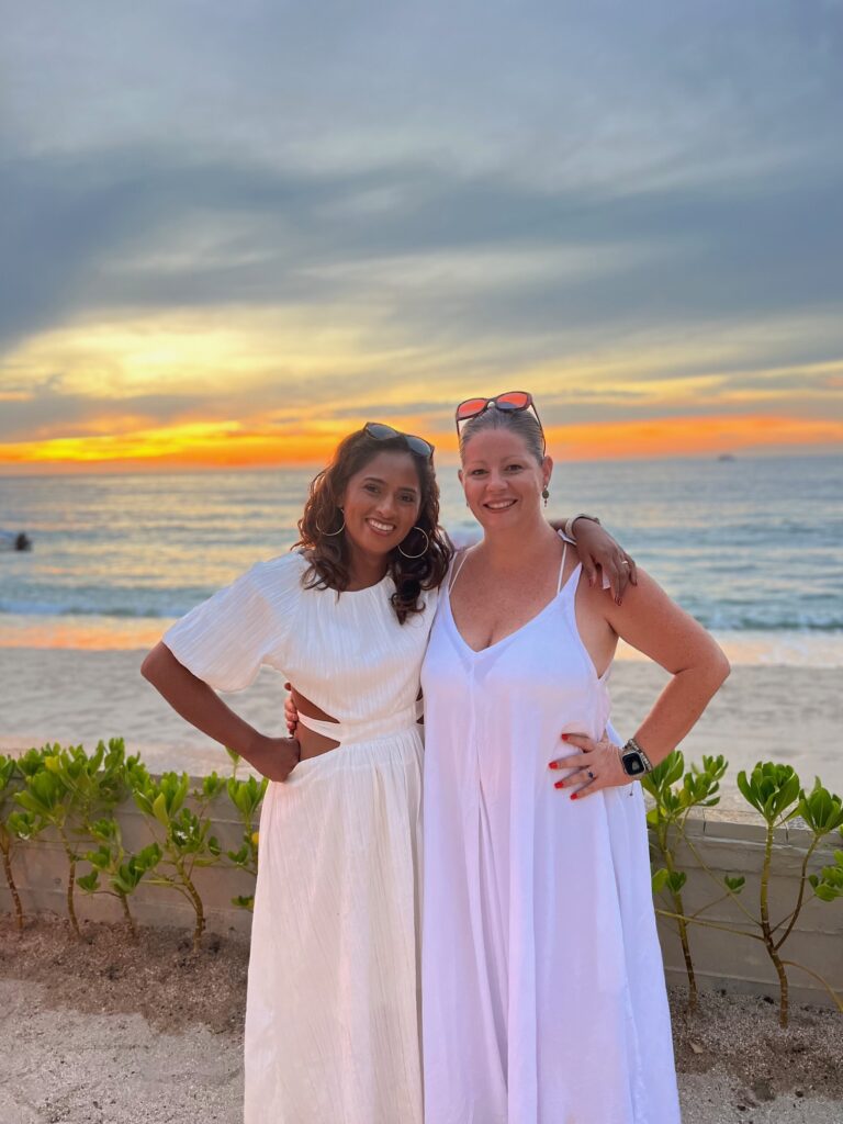 Rocio, the manager of Villa Experience, and Kelley, the manager and owner of "Events Younique by Kelley" wedding planning service, enjoying the open house event on Villa Mixto's terrace, with a beautiful sunset illuminating the event.