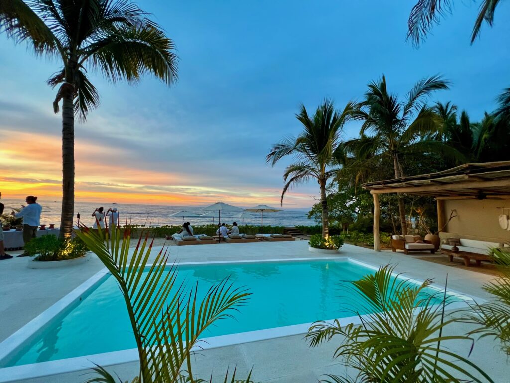 A breathtaking view of Villa Mixto's swimming pool with a picturesque sunset backdrop, highlighting the villa's tranquil ambiance and luxurious charm.