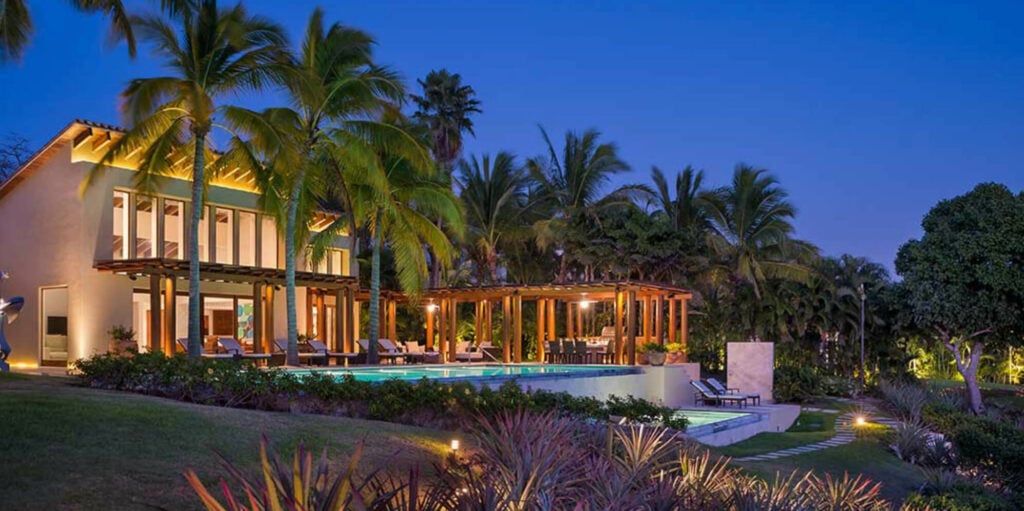 Estate Jaguar villa and lit pool seen across the garden at dusk — Punta Mita, Mexico
