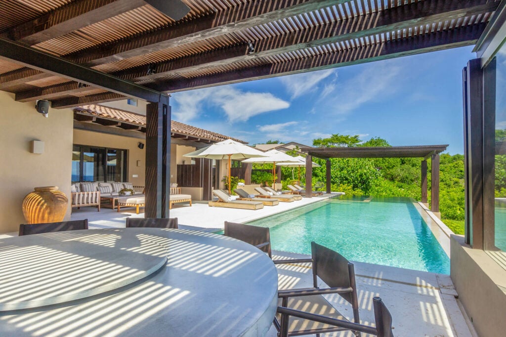 Estate La Sierra shaded round dining table beside the pool and loungers — Punta Mita Nayarit, Mexico
