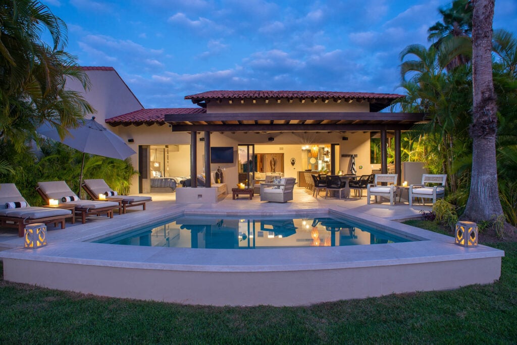 Villa Tamayo pool and lit terrace at dusk seen across the lawn — Punta Mita Nayarit, Mexico