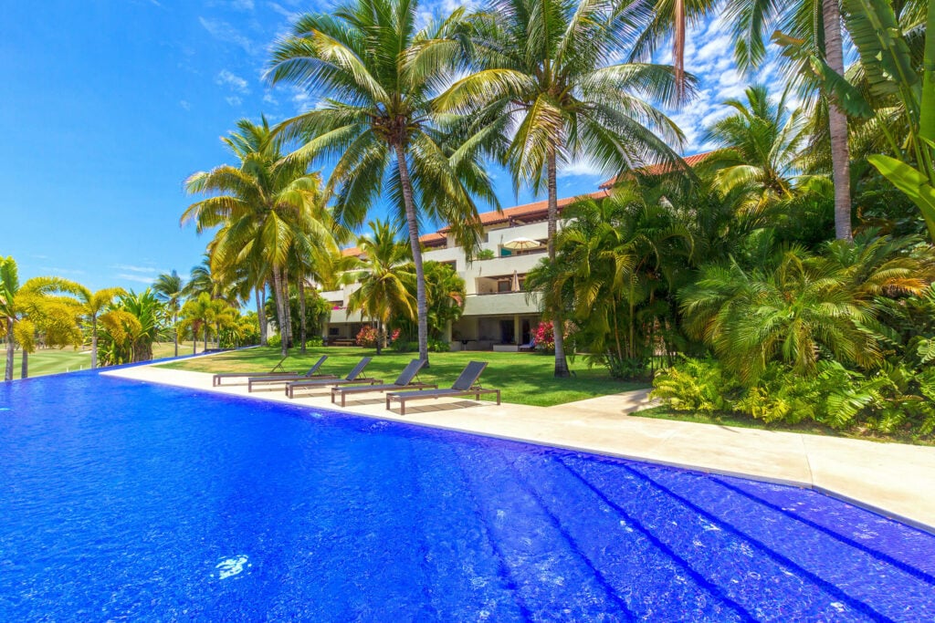 Condo Palma Azul blue pool with loungers, palm trees and the building beyond — Punta Mita Nayarit, Mexico