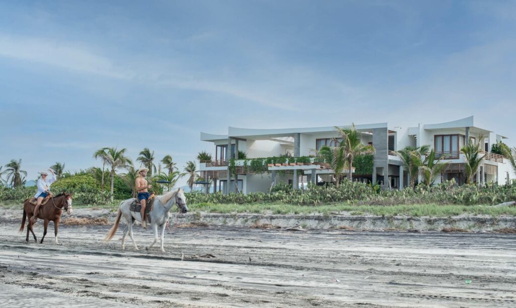 Guests enjoying horseback riding along the pristine beachfront of Niku House villa rental in Puerto Escondido.