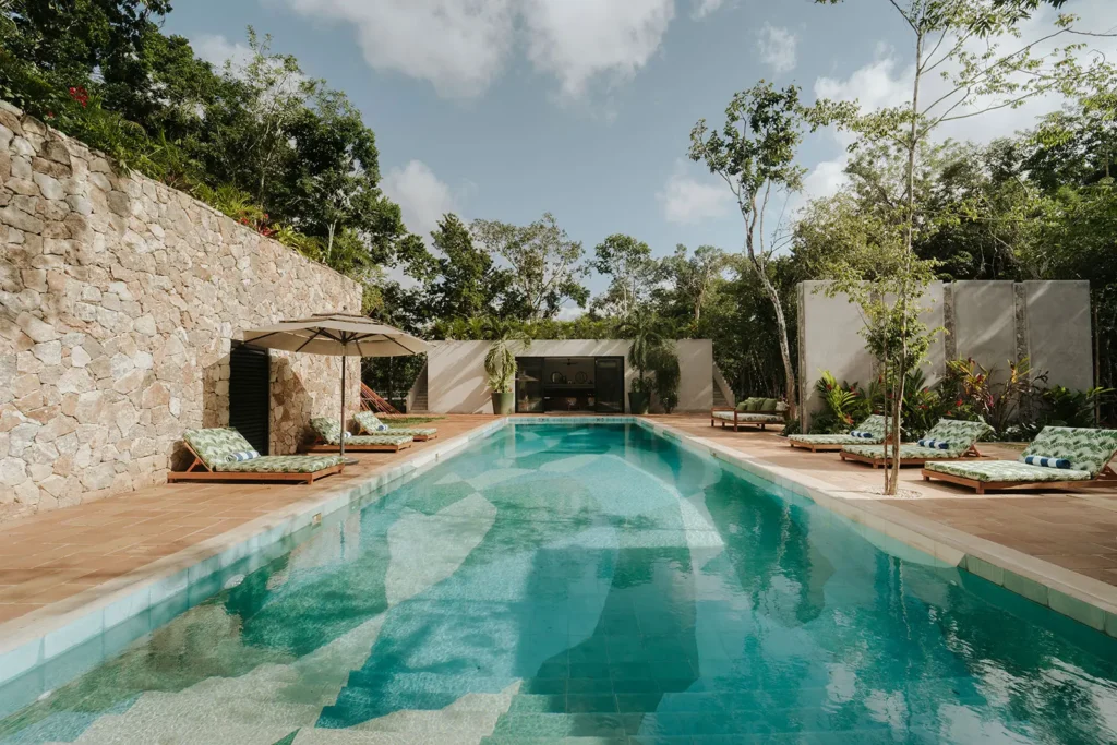 Casa Xolo pool running alongside the stone villa framed by jungle — Tulum, Mexico