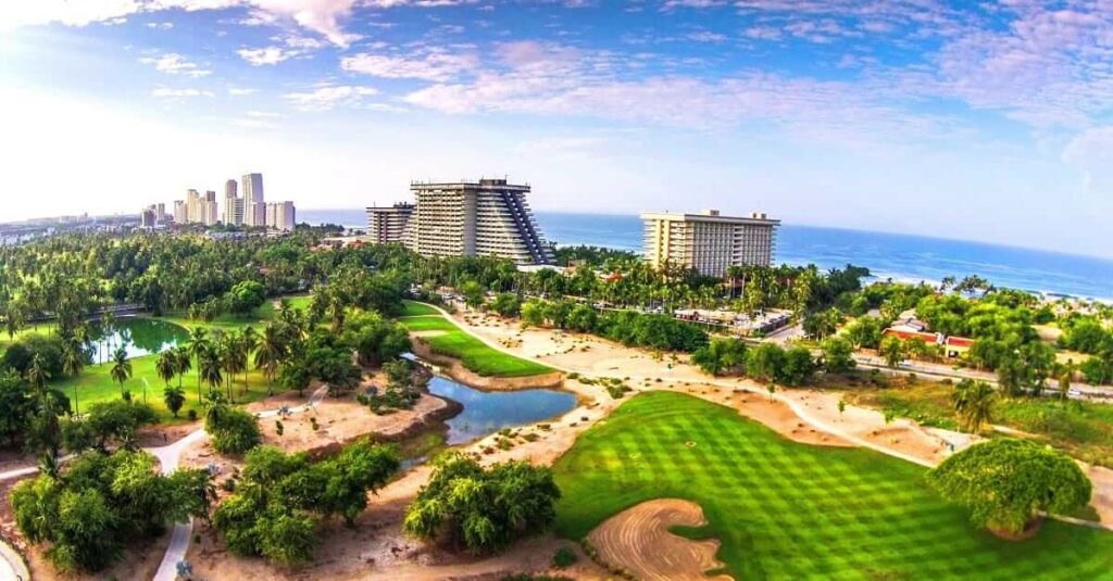 Aerial panorama capturing the vibrant Acapulco Diamante, featuring the stunning coastline, lush golf courses, and burgeoning Mundo developments.