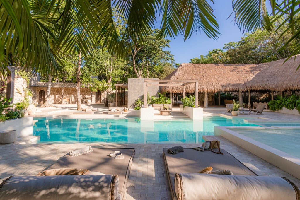 Onze Sanctuary large pool with sun loungers and thatched palapa — Xpu Ha Riviera Maya