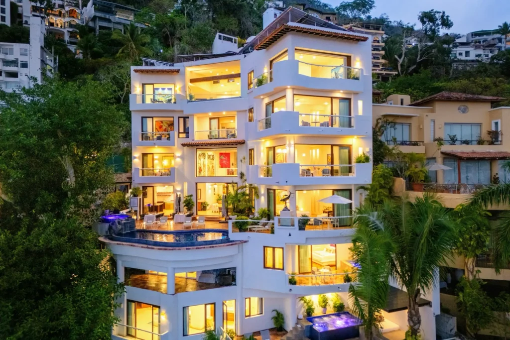 Villa Divina illuminated hillside villa at dusk with glowing balconies — Puerto Vallarta, Mexico