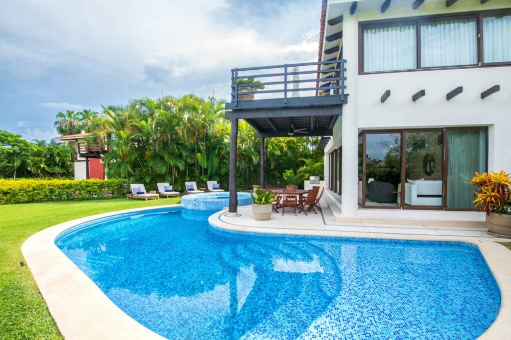 Casa Uno Mas curved pool beside the villa, lawn and row of loungers — Punta Mita Nayarit, Mexico