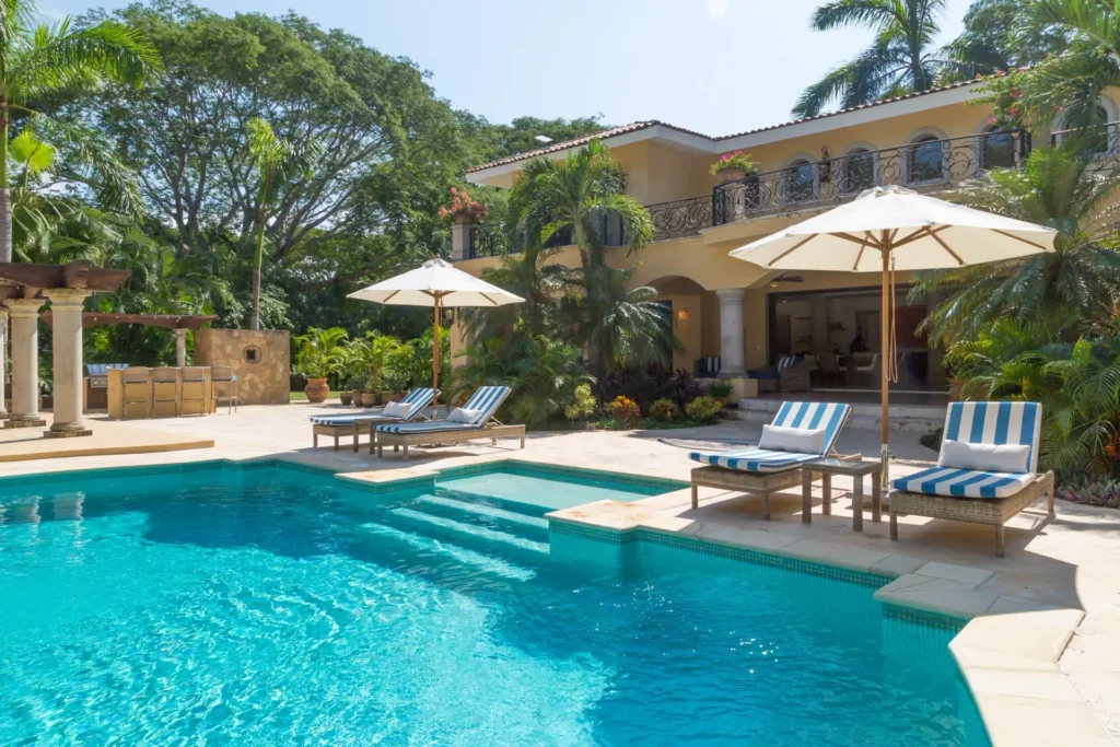 Casa Invierno pool steps and striped loungers in front of the arcaded facade — Punta Mita Nayarit, Mexico