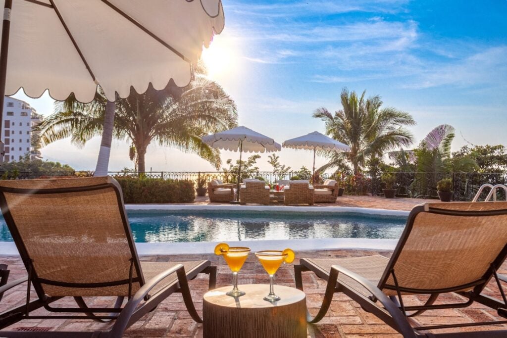 Villa Castillo two poolside loungers beside a table with orange drinks — Puerto Vallarta, Mexico
