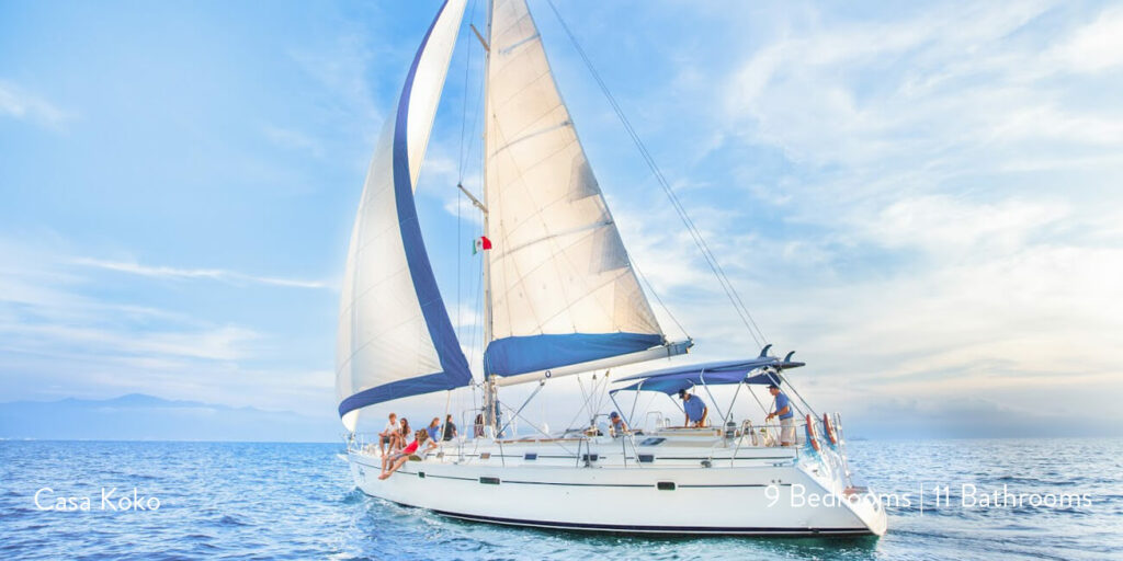 An image showing a luxurious sailboat owned by Casa Koko, cruising on the crystal-clear waters near Punta Mita, Mexico, with guests enjoying the serene ocean view.