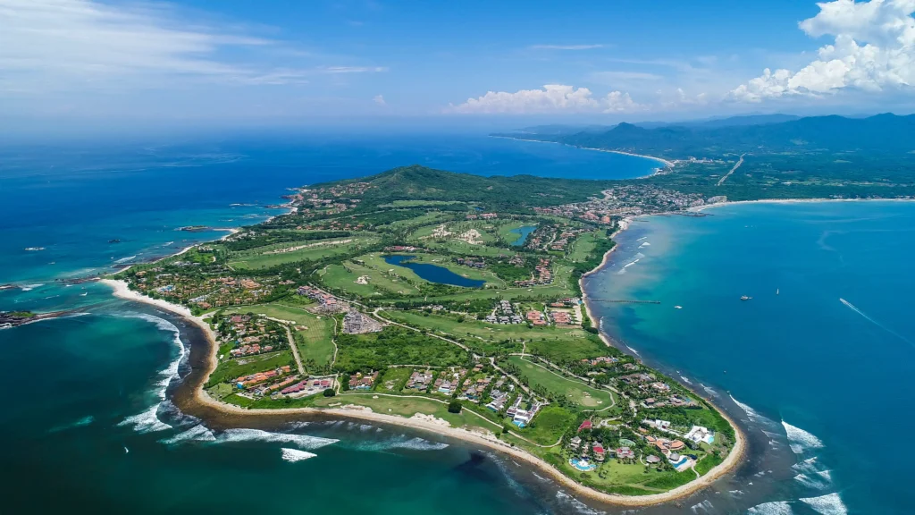 An aerial view of Punta Mita, Mexico, showcasing the stunning coastline, lush greenery, and luxurious beachfront properties.