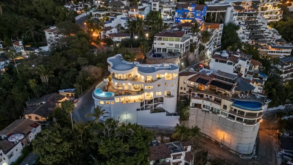 Casa Paakat aerial night view of the lit villa amid the town's hillside lights — Puerto Vallarta, Mexico