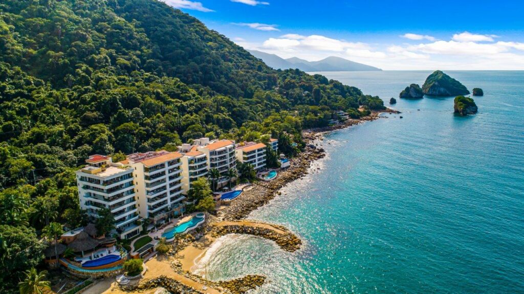 Aerial view of the Sierra del Mar Los Arcos gated community with beachfront properties and lush green hills.