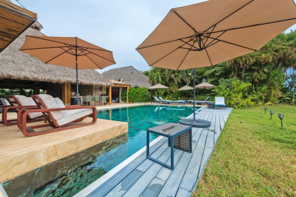 Casa Lapa Lapa wood loungers and umbrellas beside pool and thatched pavilions — Punta Mita Nayarit, Mexico