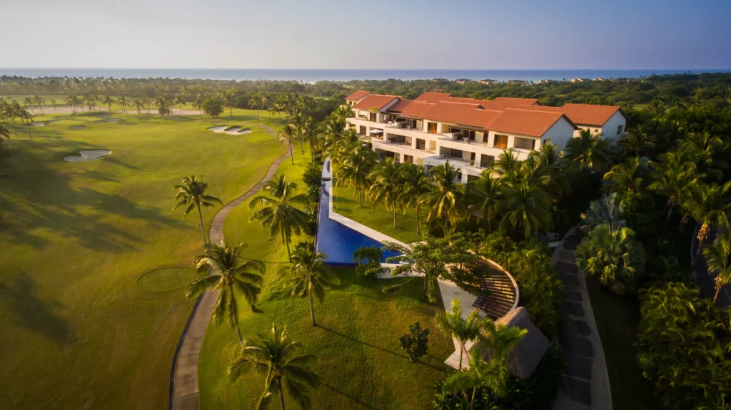 PH Condo Pacifico aerial of a terracotta-roof building, pool, palms and golf course — Punta Mita Nayarit, Mexico