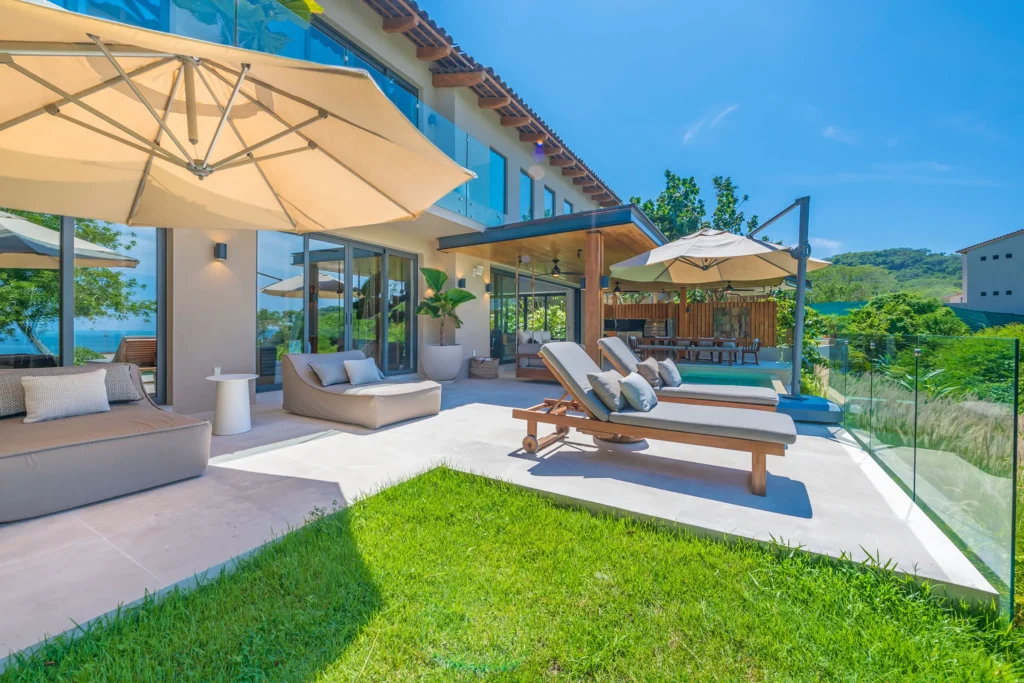 Villa Mataiza patio loungers and umbrellas beside a lawn and glass railing — Punta Mita Nayarit, Mexico