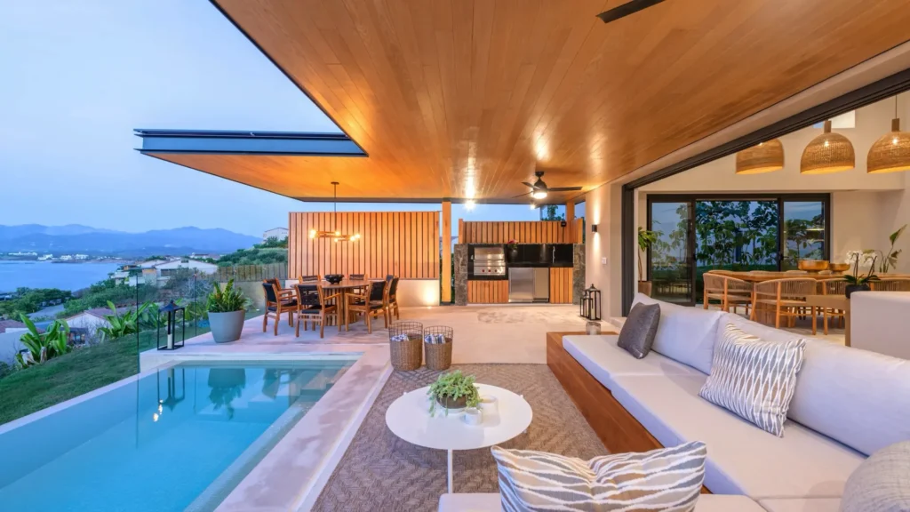 Casa Patrón poolside built-in sofa beneath a wood ceiling facing the grill and bay — Punta Mita Nayarit, Mexico