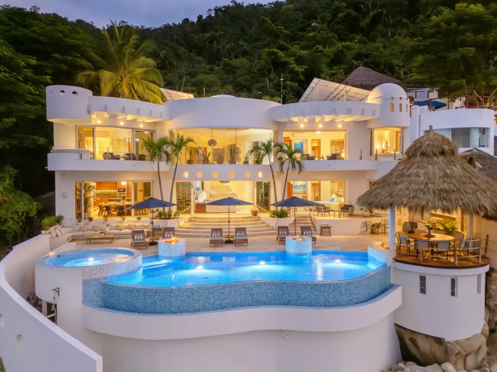 Casa Nahui villa illuminated at dusk above the clover-shaped pool — Puerto Vallarta, Mexico