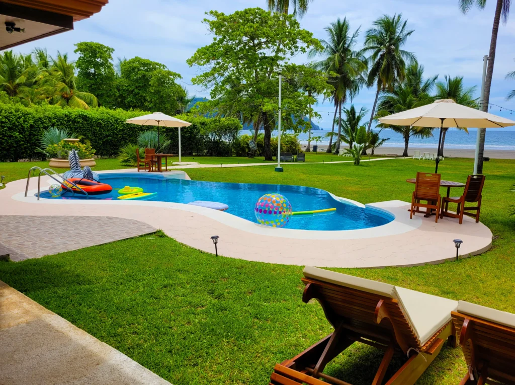 Villa Amor del Mar in Tango Mar, Costa Rica: tropical pool with ocean view, palm trees, loungers, and greenery.
