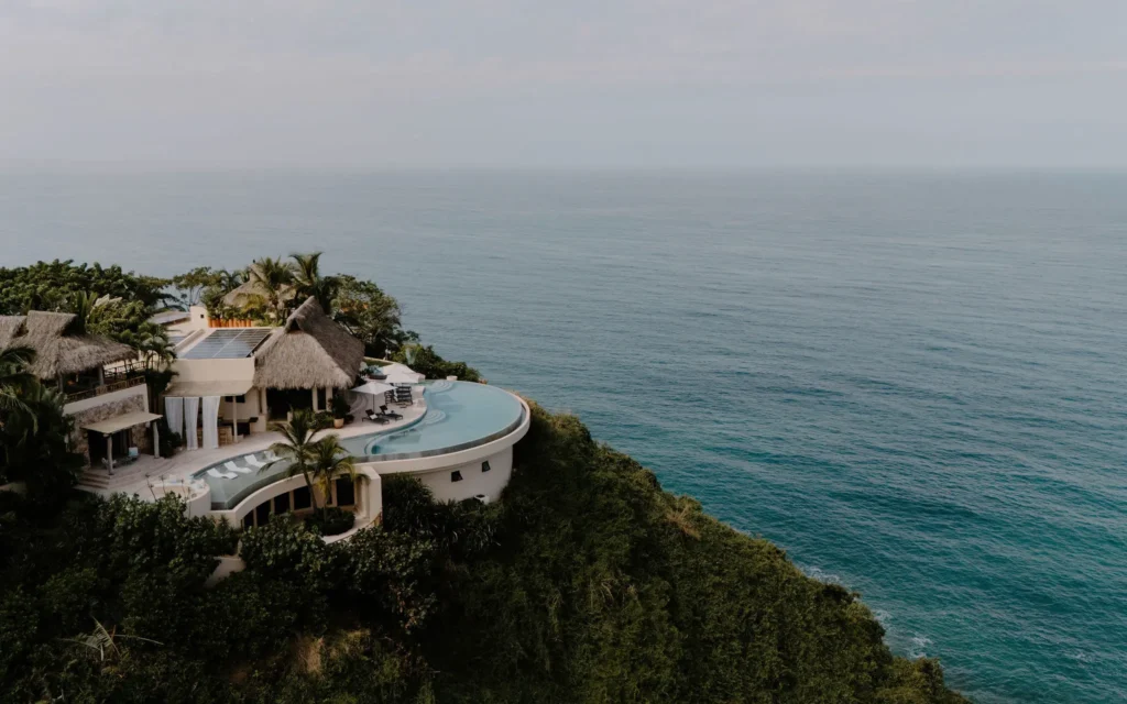 Casa La Joya aerial view of the clifftop villa and curved pool above the ocean — Punta Mita Nayarit, Mexico