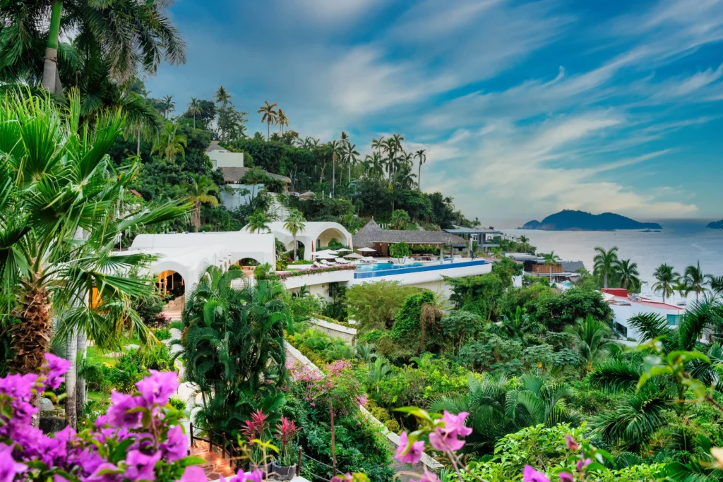 Villa Sabalo white arched buildings and pool amid palms above the sea and island — Acapulco, Mexico
