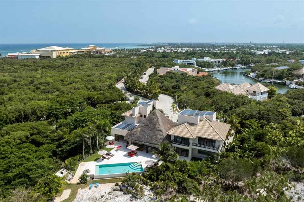 Casa Cangrejo Feliz aerial view of a villa with a pool, thatched roof and solar panels — Puerto Aventuras, Mexico