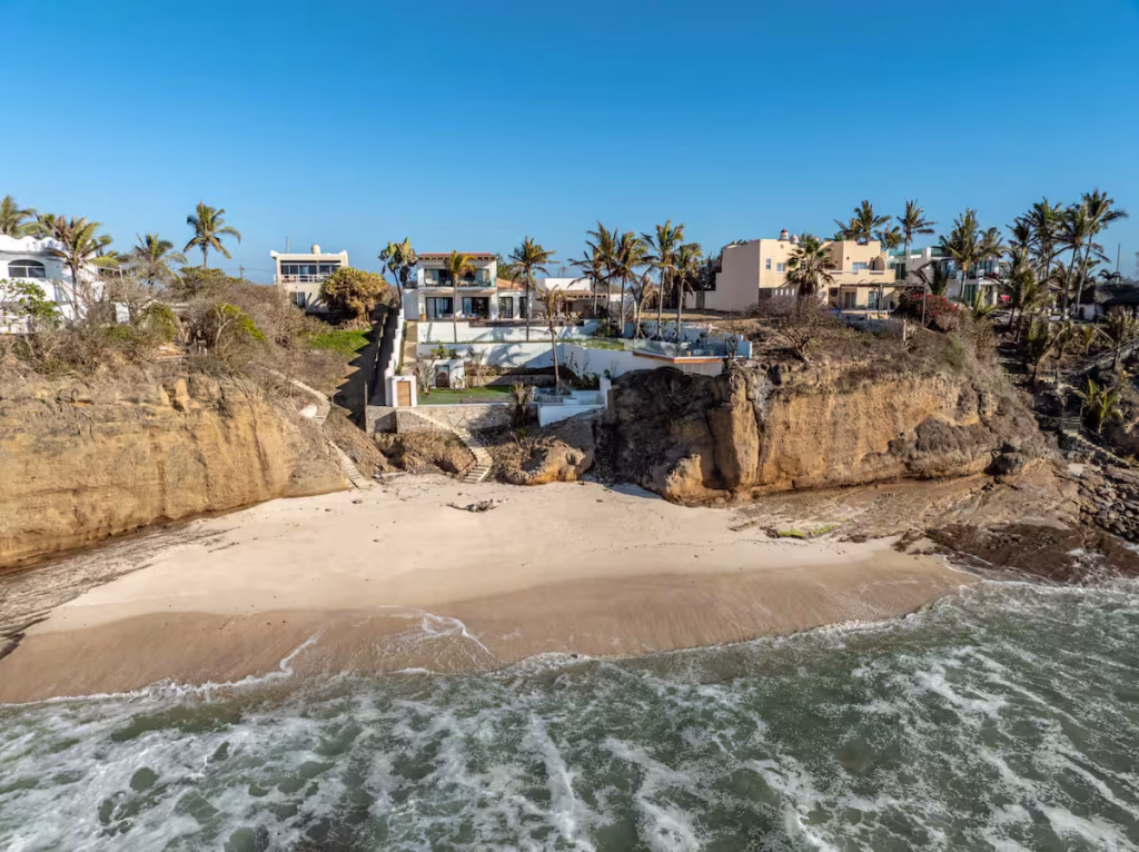 Casa Hayam aerial view of ocean surf entering a cove below cliffside homes — Punta Mita Nayarit, Mexico
