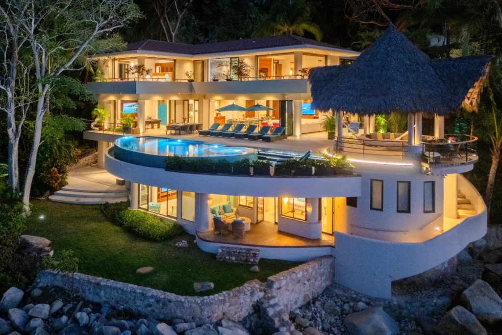 Casa Pena del Mar, in Sierra del Mar, Puerto Vallarta, overlooks the rocky waterfront with pool, gazebo, and lush greenery.