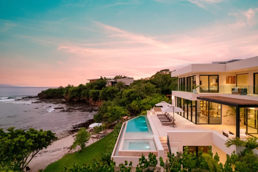 Casa Todos Juntos, Bolongo, Punta de Mita: Modern beachfront villa with infinity pool and ocean views amid lush, rocky coast.