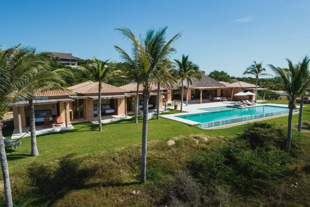 Casa Constantia aerial view of the tiled-roof villa, palm lawn, and long pool — Puerto Escondido, Mexico