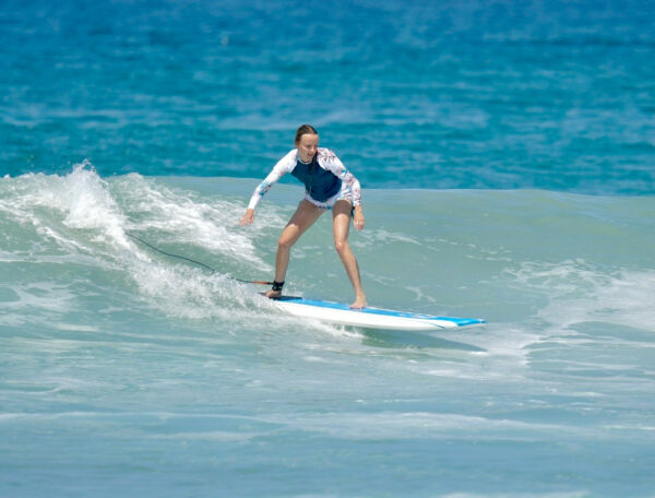 Woman riding a gentle wave during a beginner surf lesson in Punta Mita
