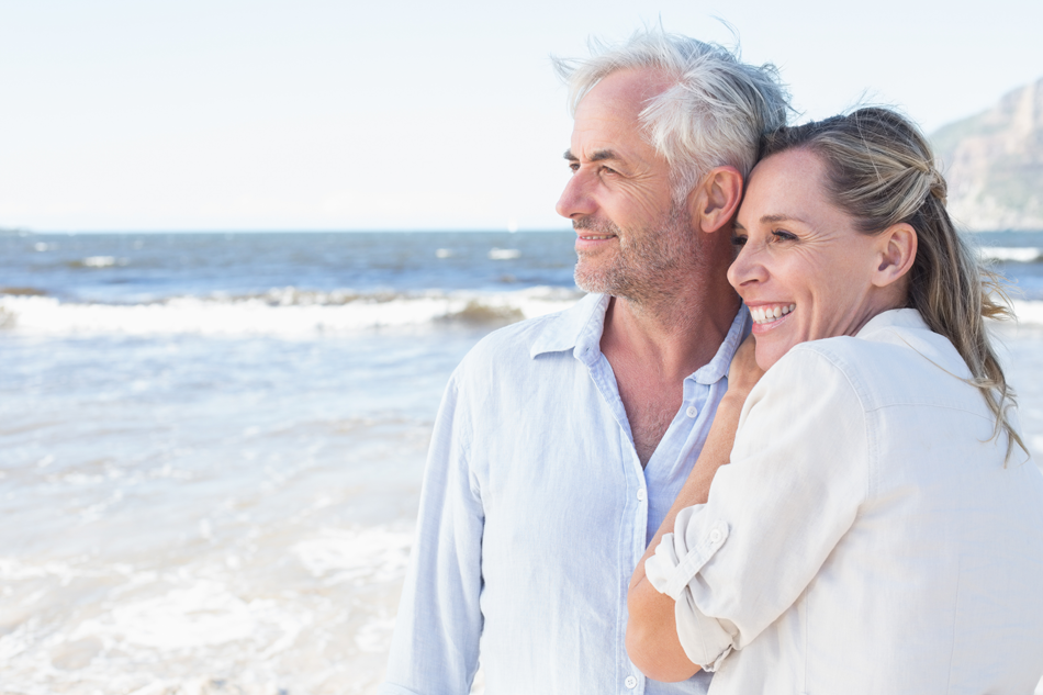 Smiling couple on a sunny Mexico beach, enjoying peace of mind with Mexico travel insurance.