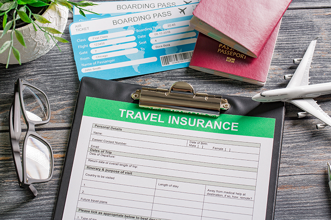 Mexico travel insurance form with passports, boarding passes, eyeglasses, and a toy airplane on a wooden table.