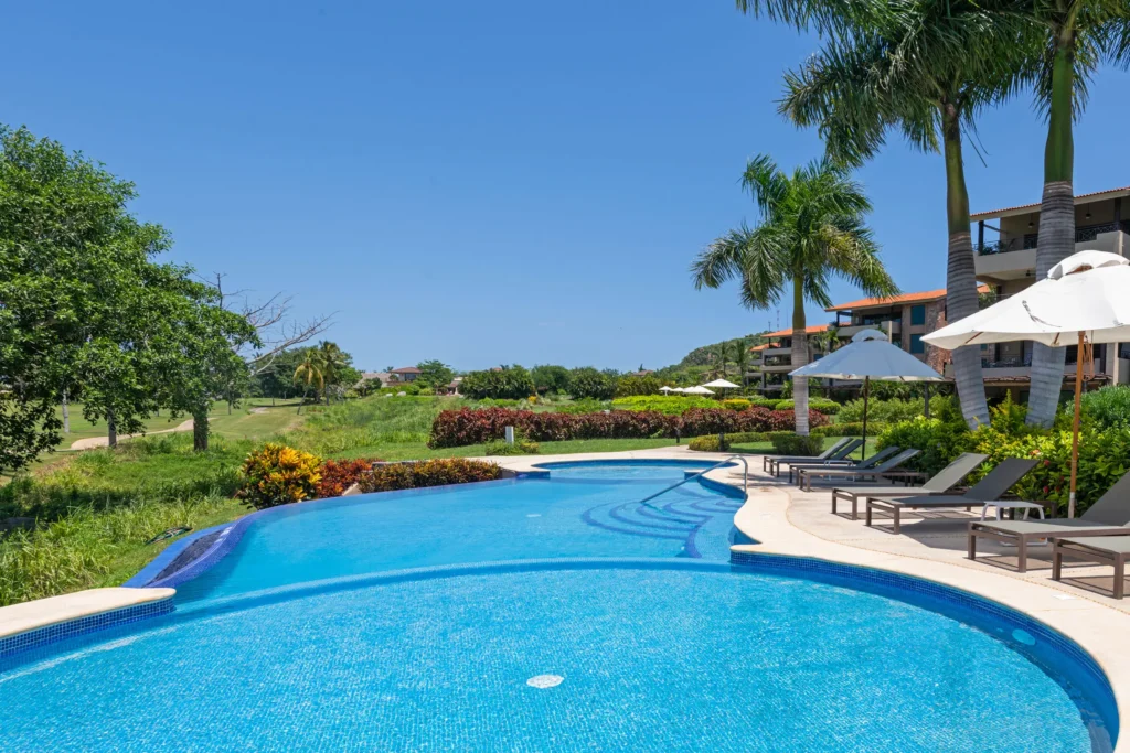 Condo Hacienda de Mita 903 the curving pool with loungers and umbrellas beside the lawn — Punta Mita, Mexico