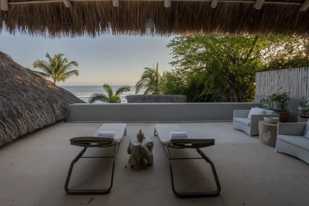 Two loungers under a thatched roof above the garden — Casarena, Punta de Mita