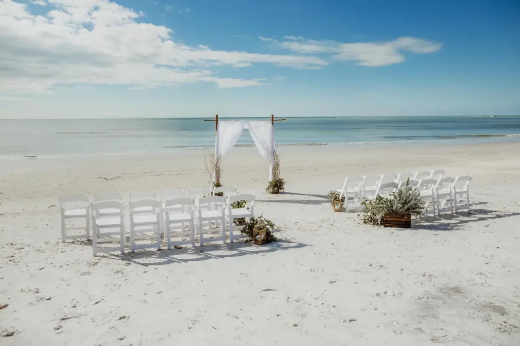 A ceremony arch and two blocks of white chairs set out on an empty beach in Punta Mita