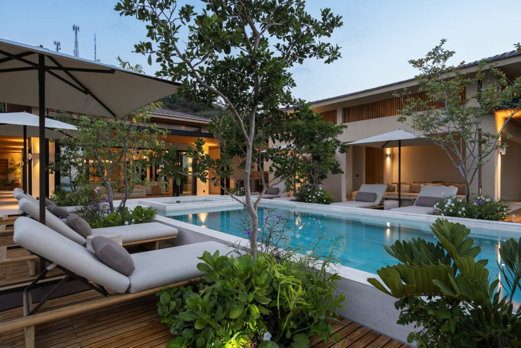 Casa Tuki loungers and umbrellas around the lit pool at dusk — Punta Mita, Mexico