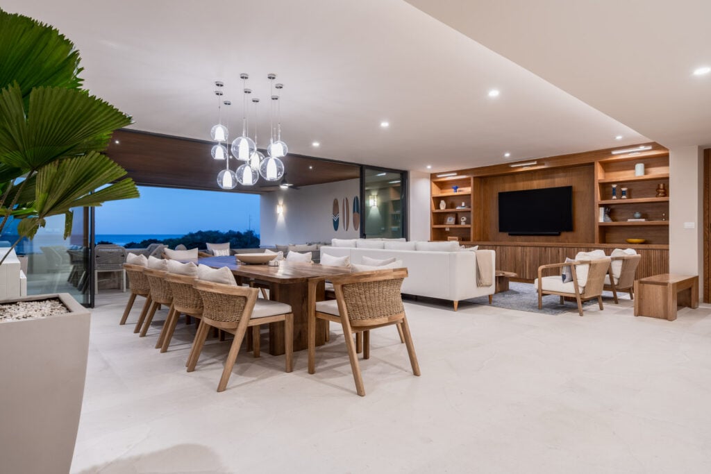Condo Amor y Surf the dining table and living room open to the terrace at dusk — Punta Mita, Mexico