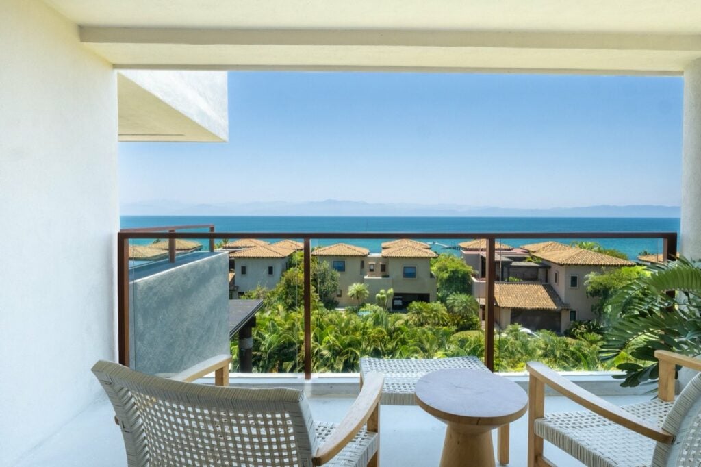 Condo El Encanto 1021 balcony with two chairs and a round table overlooking roofs and ocean — Punta Mita Nayarit, Mexico