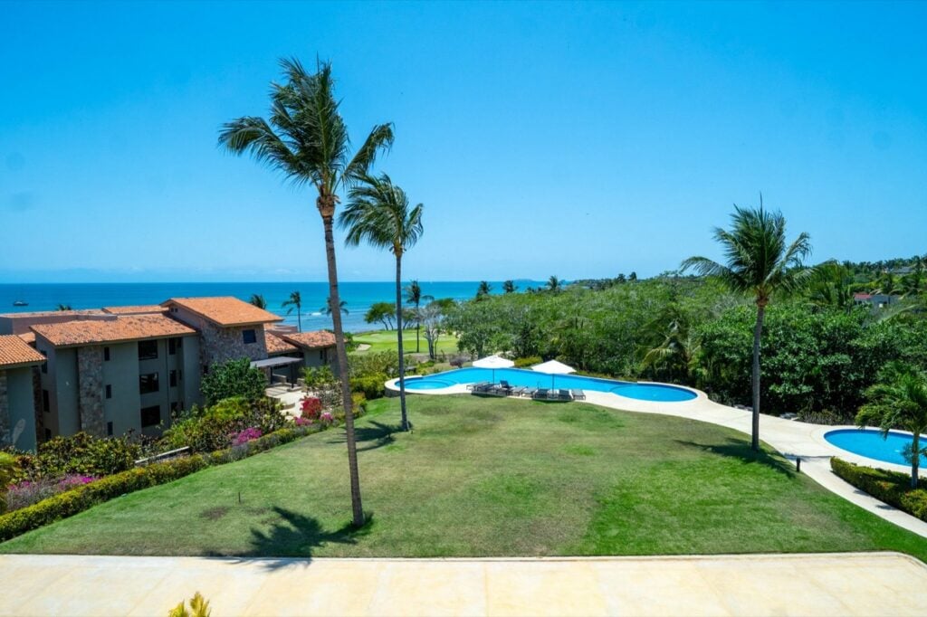 Condo Hacienda de Mita 705 elevated view over lawn, pools, palms, and ocean — Punta Mita Nayarit, Mexico