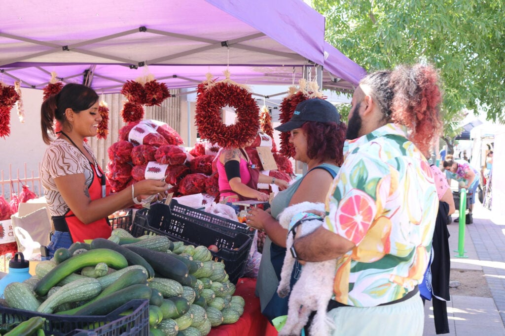 Customers buying vegetables at an outdoor market stall at La Cruz de Huanacaxtle