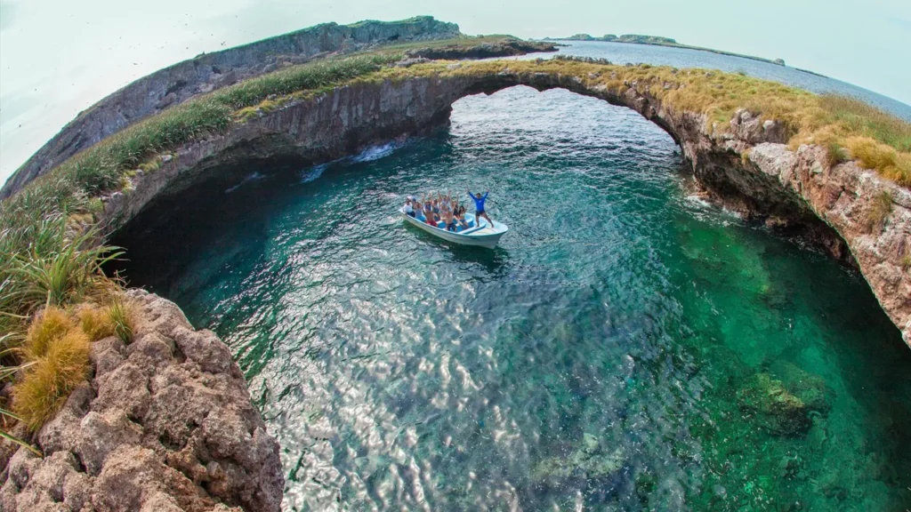 An aerial of a passenger boat inside a round rocky cove on the islands