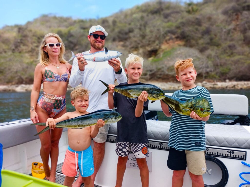 A family on the back of a boat holding the morning's three fish