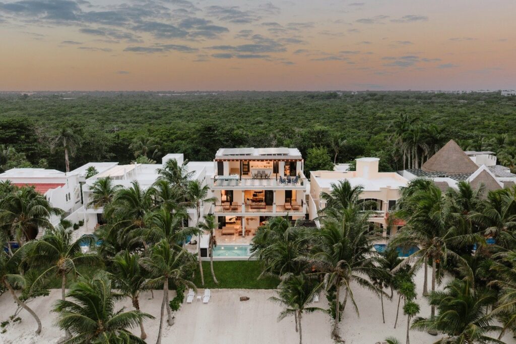 Villa Dulce Vida wide aerial view between a palm-lined beach and forest at dusk — Riviera Maya, Mexico